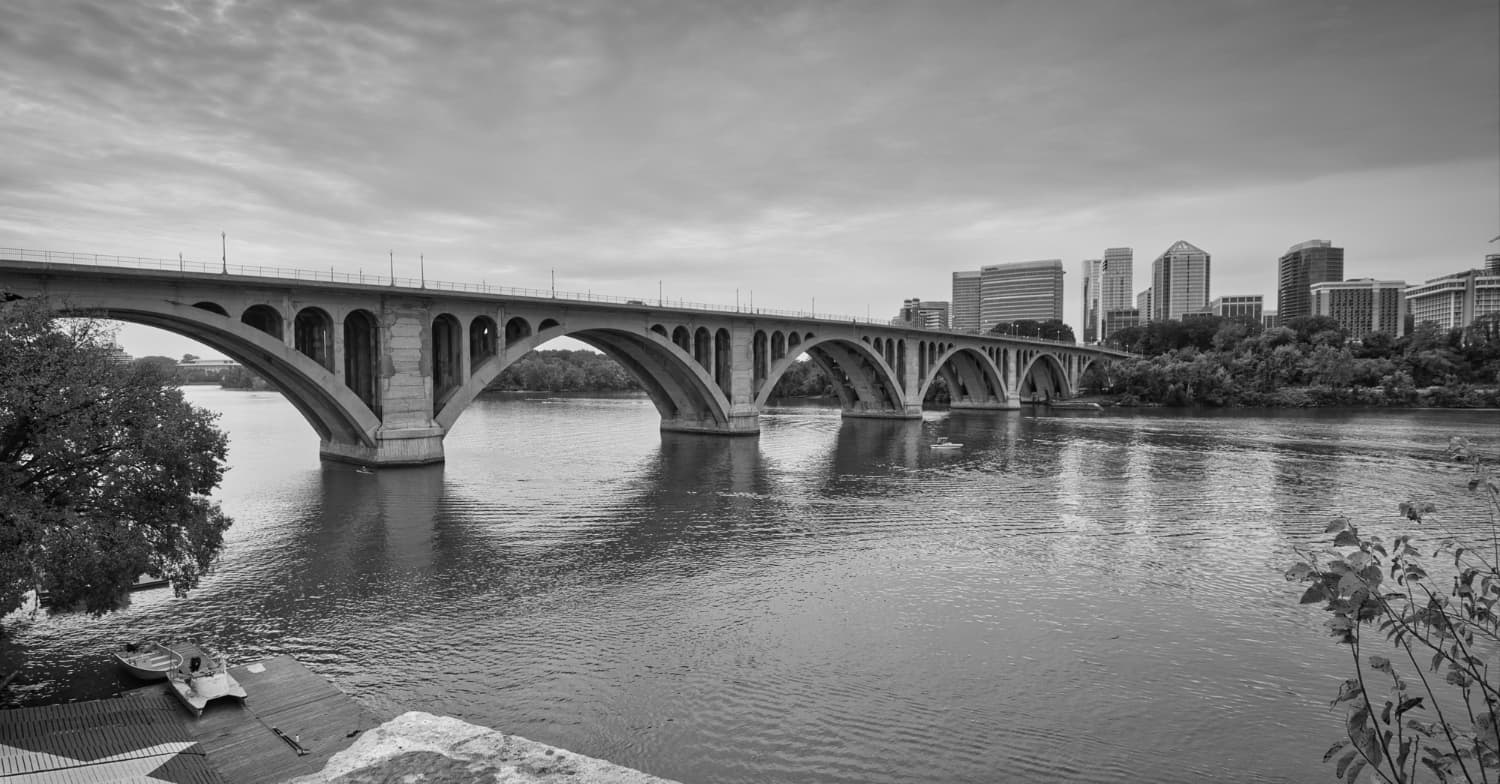 Bridge spanning a river with city skyline in the background